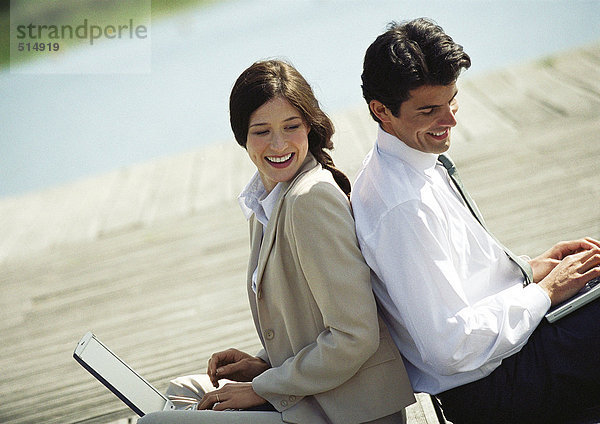 Geschäftsmann und Frau Rücken an Rücken mit Laptop-Computern  Taille nach oben  Neigung