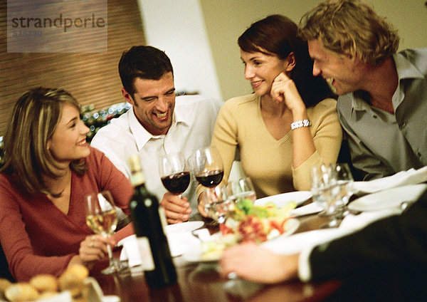 Jugendgruppe am Tisch  Wein trinken und lachen