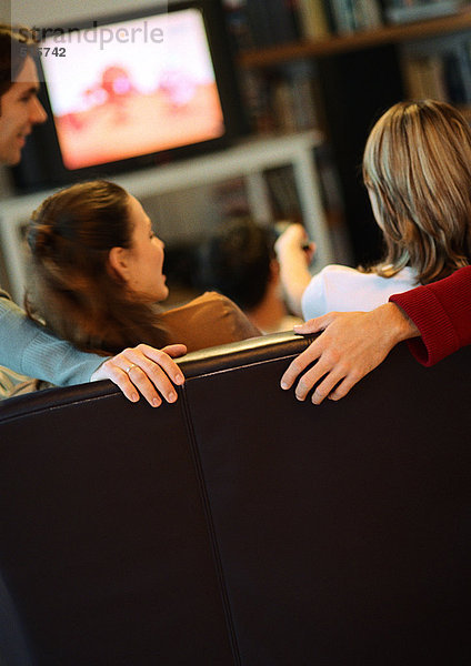 Menschen sitzen auf der Couch  reden  Rückansicht  Fernseher im Hintergrund