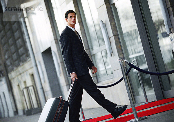 Geschäftsmann zu Fuß mit Gepäck draußen  Seitenansicht