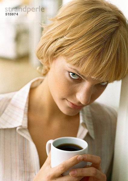 Teenager-Mädchen ruht Kopf an der Wand  hält Kaffee  schaut in die Kamera