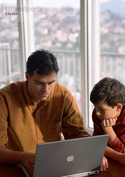 Vater und Sohn arbeiten am Computer.