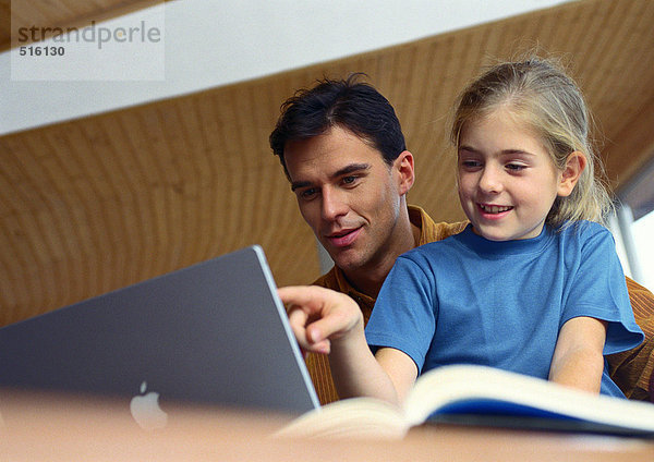 Vater und Tochter arbeiten zusammen am Computer.