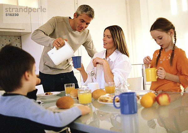 Familie beim gemeinsamen Frühstücken  Vater beim Trinken
