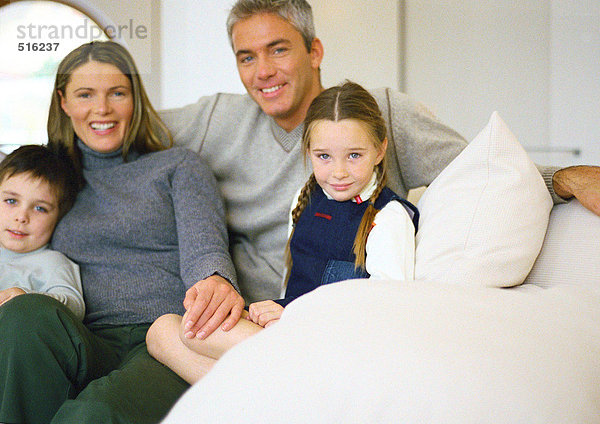 Mann  Frau und zwei kleine Kinder sitzen zusammen auf der Couch  Porträt