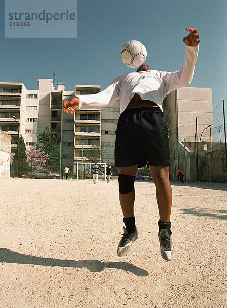 Mann fängt Fußball auf der Brust im städtischen Spielplatz ein