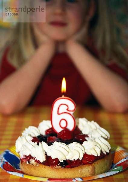 Kleines Mädchen mit Geburtstagskuchen und Kerze  Schwerpunkt Vordergrund
