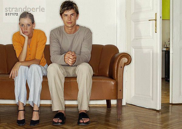 Mann und Frau sitzen Seite an Seite auf dem Sofa.