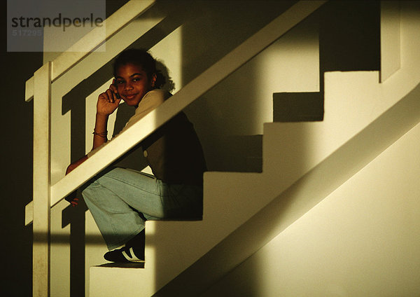 Junges Mädchen auf der Treppe sitzend  telefonierend  lächelnd