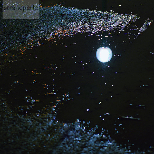 Reflektion der Straßenbeleuchtung in der Pfütze  Nacht