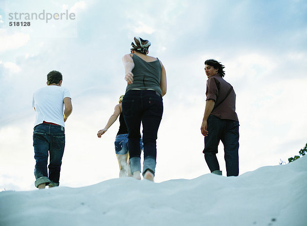 Vier Personen auf Sand  Rückansicht