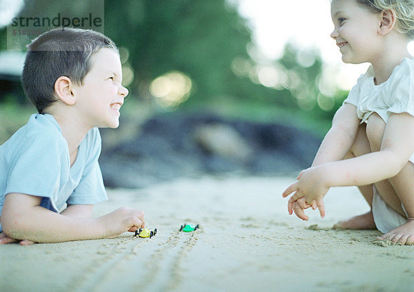 Kinder spielen auf Sand  Seitenansicht