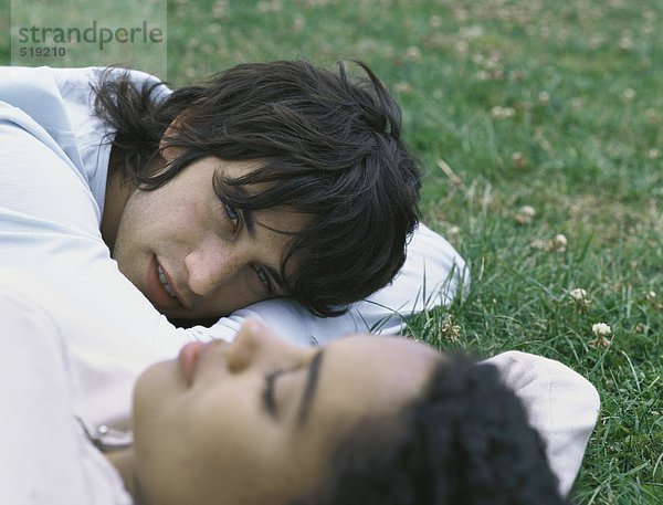 Junger Mann und junge Frau auf Gras liegend