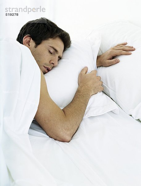 Mann auf dem Bauch liegend auf dem Bett mit geschlossenen Augen