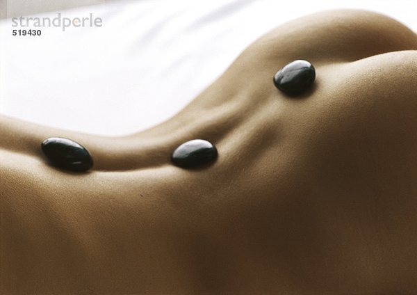 Nackter Rücken mit schwarzen Steinen auf dem Rücken  Nahaufnahme