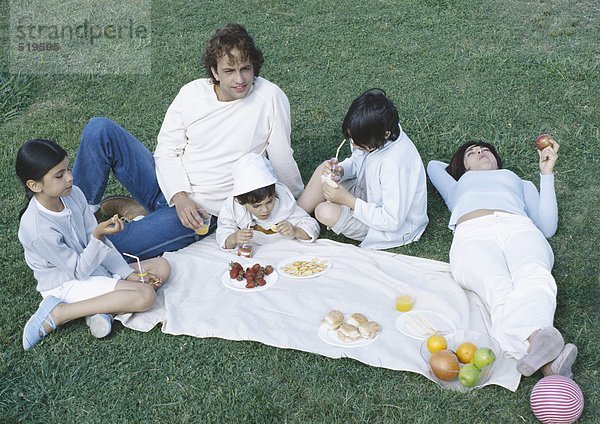 Eltern mit Jungen und Mädchen beim Picknick auf dem Rasen