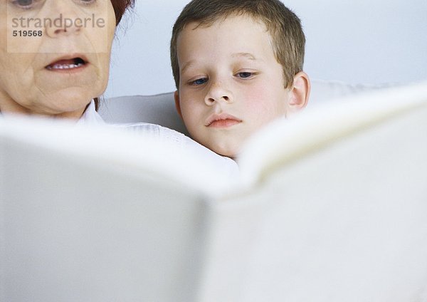 Großmutter liest Buch für Jungen