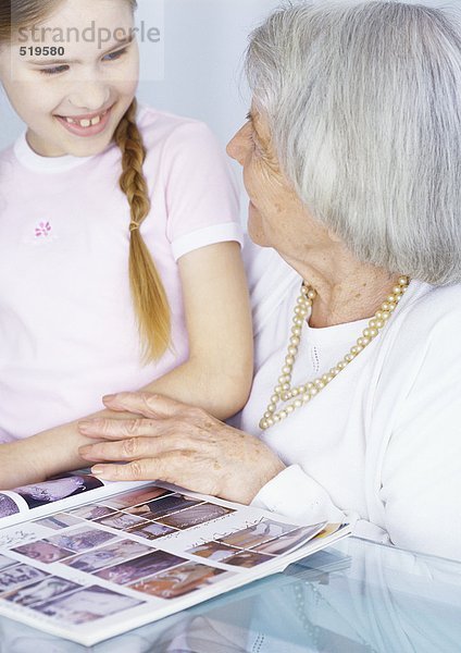 Großmutter und Enkelin schauen sich gemeinsam das Magazin an