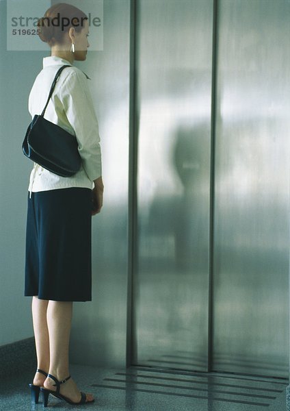 Frau wartet auf Aufzug  volle Länge
