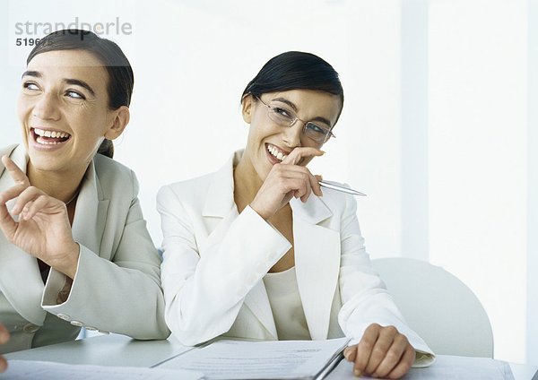 Zwei Geschäftsfrauen lachend  zur Seite schauend