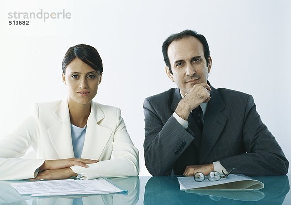Geschäftsmann und Geschäftsfrau am Tisch sitzend mit Unterlagen