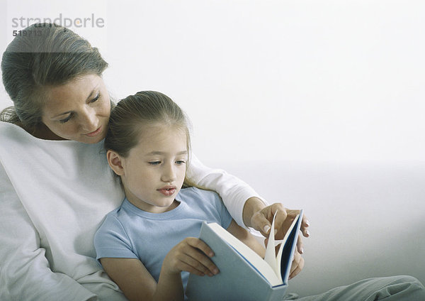 Frau und Mädchen lesen gemeinsam Buch