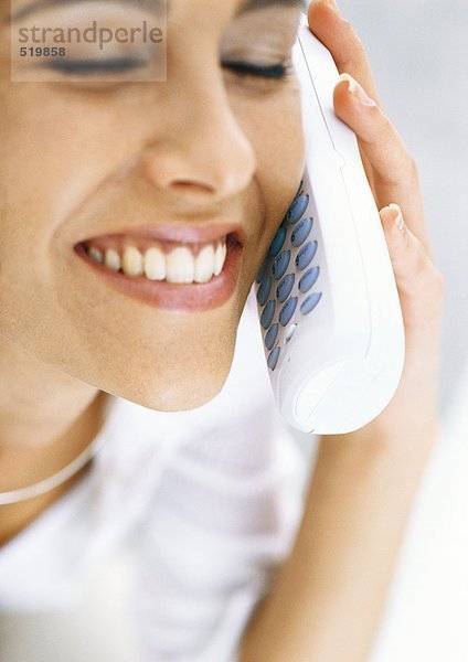 Frau am schnurlosen Telefon mit geschlossenen Augen  lächelnd