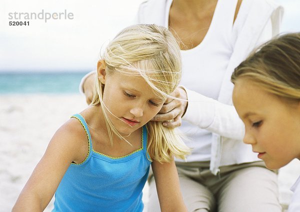 Zwei Mädchen und Mutter am Strand