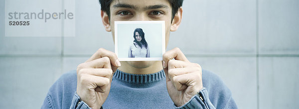Junger Mann hält Foto von junger Frau hoch