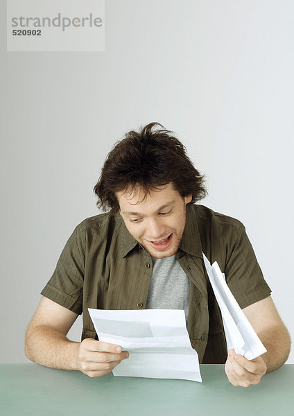 Junger Mann liest Brief  lächelnd