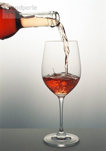 Ein Glas Roséwein ausgießen