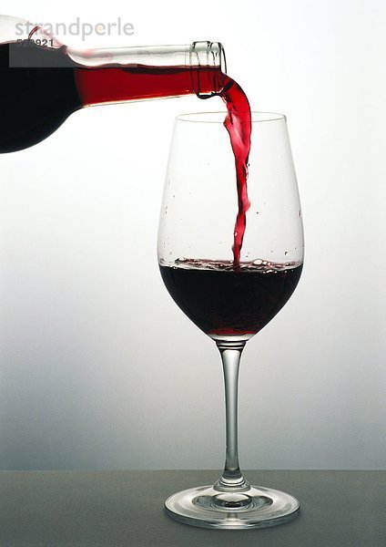 Gießen eines Glases Rotwein