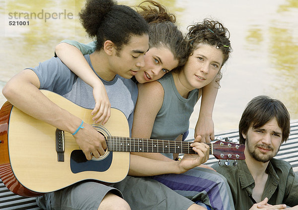 Vier junge Freunde versammelten sich um die Gitarre.