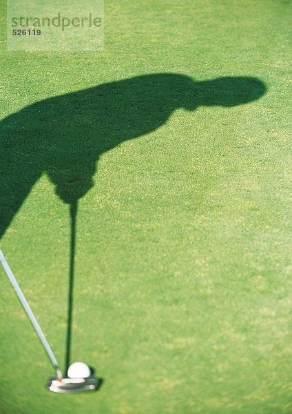 Schatten des Golfspielers beim Putten