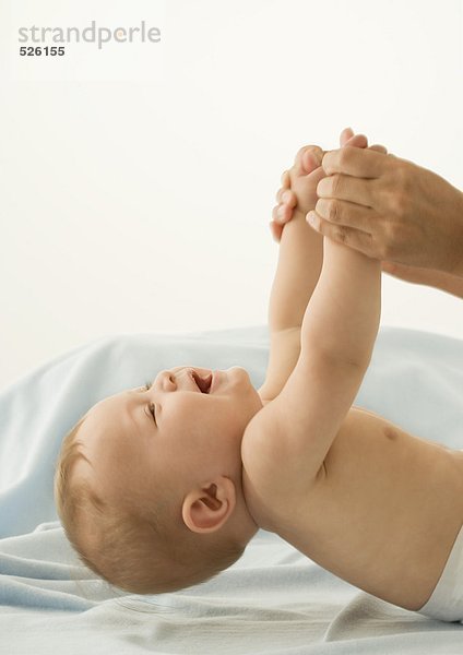 Elternteil hebt das Baby mit den Händen an.