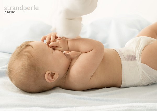 Baby mit Spielzeug  Gesicht bedeckend und lachend