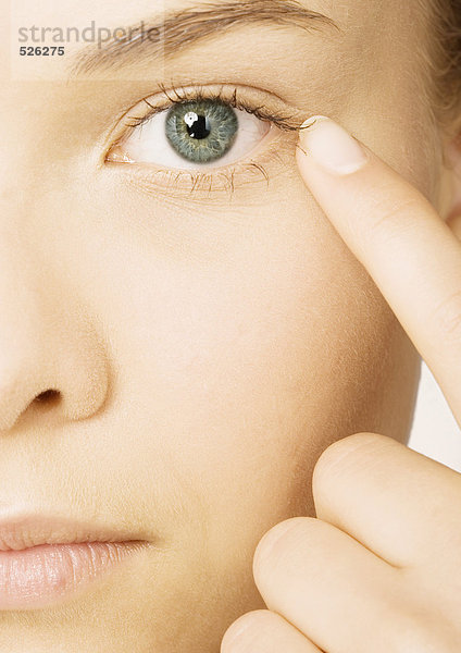 Frauengesicht mit Finger neben dem Auge  extreme Nahaufnahme