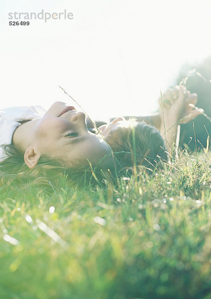 Junge und Mädchen liegen zusammen auf Gras.