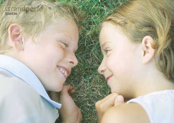 Junge und Mädchen im Gras liegend  lächelnd