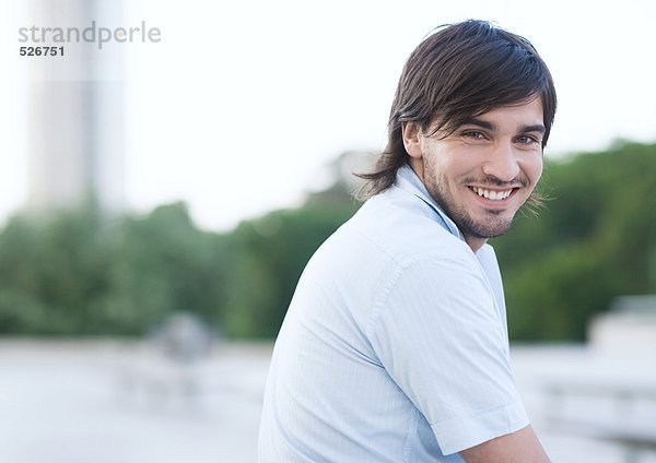 Junger Mann lächelt im Stadtpark  Portrait