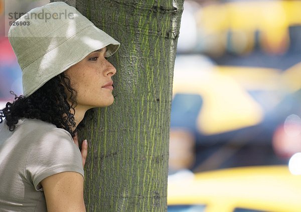 Junge Frau am Baum stehend