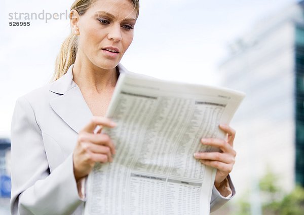 Geschäftsfrau beim Lesen von Finanzseiten der Zeitung