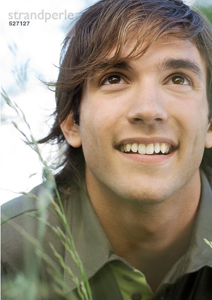 Junger Mann im Gras lächelnd  Portrait