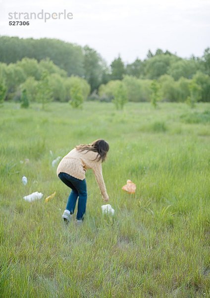 Frau beim Aufnehmen von Plastiktüten im Feld