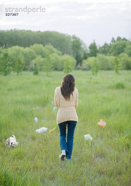 Frau auf dem Feld mit Plastiktüten verstreut