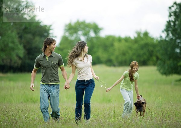 Junges erwachsenes Paar mit Mädchen und Hund unterwegs