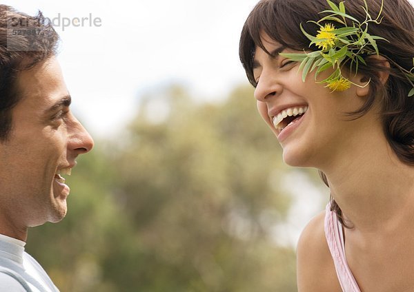 Junges Paar lacht  Frau trägt Blumen hinter dem Ohr