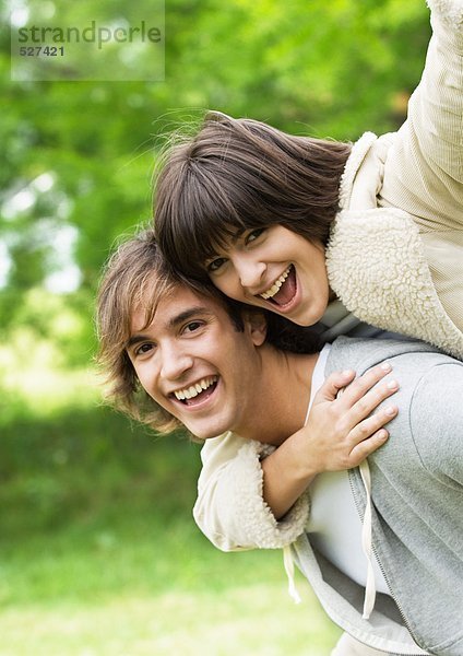 Porträt eines lächelnden jungen Paares  Frau auf dem Rücken des Mannes