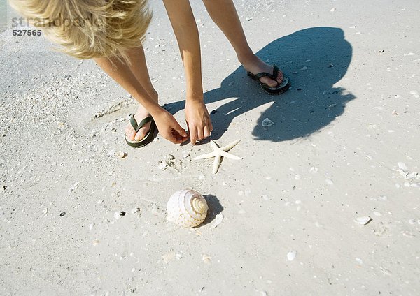 Kind holt Muscheln am Strand ab