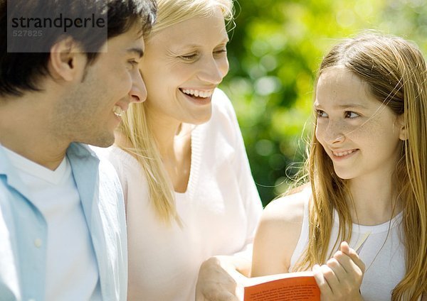 Mädchen hält Buch  lächelt die Eltern an.